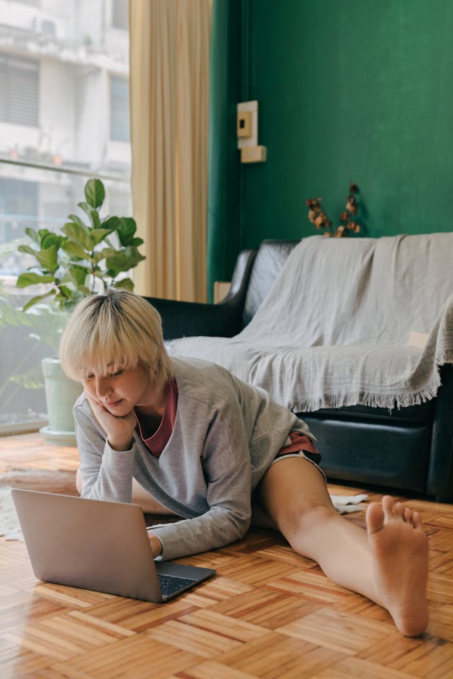 young woman in a private stress release session on the floor on a laptop with one leg out.